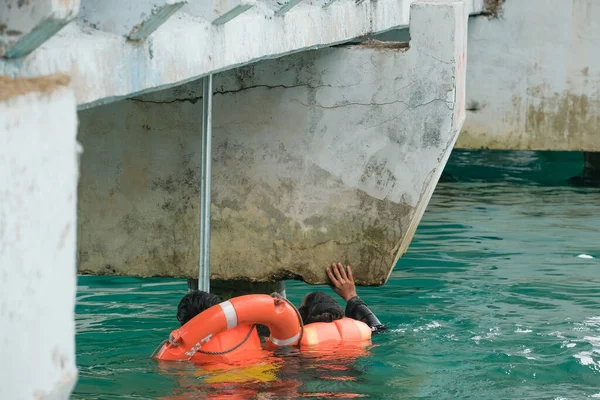 Tioman, Malezya - 20 Nisan 2022: İnşaat işçisi beton bir iskeleyi onarmak için deniz suyunun üzerinde yapı iskelesi kuruyor.