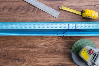Worker using grinding machine to cut steel roof batten.