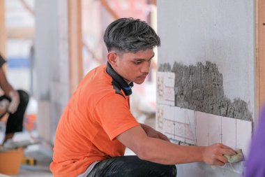 Muadzam Shah, Malaysia - August 25th, 2022: College students  laying ceramic tiles on the wall  in bricklaying workshop