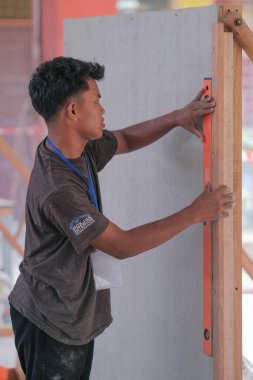 Muadzam Shah, Malaysia - August 25th, 2022: College students  laying ceramic tiles on the wall  in bricklaying workshop