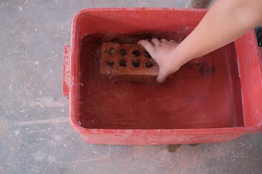 Üniversite öğrencileri tuğla örme atölyesinde tuğla duvar inşaatında çalışıyor.