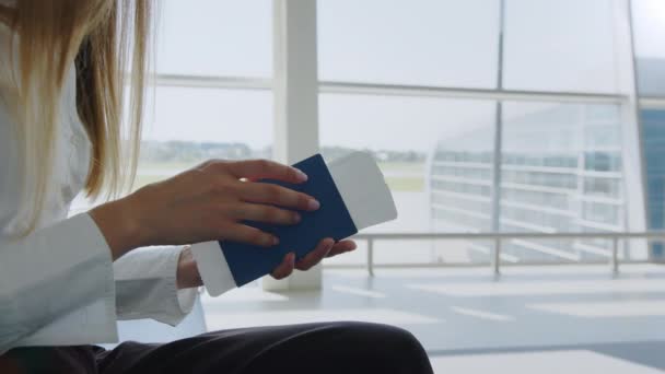 Κοντινό πλάνο, η Woman κρατά αεροπορικά εισιτήρια και διαβατήρια στα χέρια της με φόντο τους άδειους μετρητές check-in στο αεροδρόμιο. Ταξιδεύοντας με αεροπλάνο. Έγγραφα εισιτηρίων για επιβίβαση σε αεροπλάνο — Αρχείο Βίντεο
