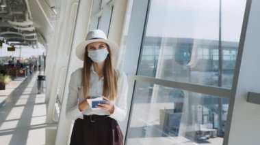 Havaalanındaki güzel iş kadını, mesaj göndermek için telefonu kullanıyor, şirket binasının penceresinin yanında duruyor, kameraya bakıyor. Kızın elinde biletler var ve...