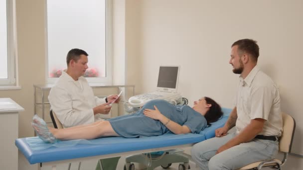 Médico dando imágenes de rayos X a marido con esposa embarazada — Vídeos de Stock