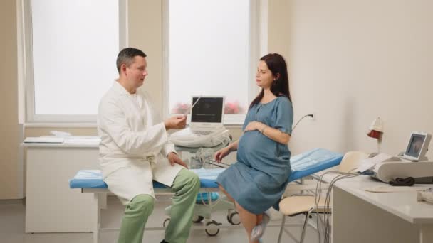 Γιατρός δίνει εικόνες μετά από υπερηχογράφημα σε έγκυο γυναίκα — Αρχείο Βίντεο