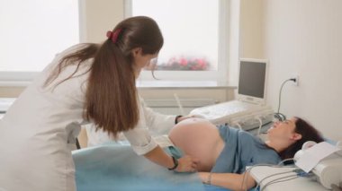 Erkek jinekolog, hamile kadını ultrasonla muayene ediyor.