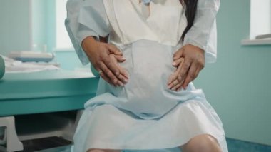 Kafkasyalı hamile, hastane koğuşunda kasılmalar sırasında çok acı çekiyor. Arkasında durup ona masaj yapan tıbbi giysili bir koca. Destek ve aşk kavramı