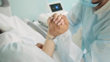 Doğum sırasında hamile bir kadının elini tutan koca.