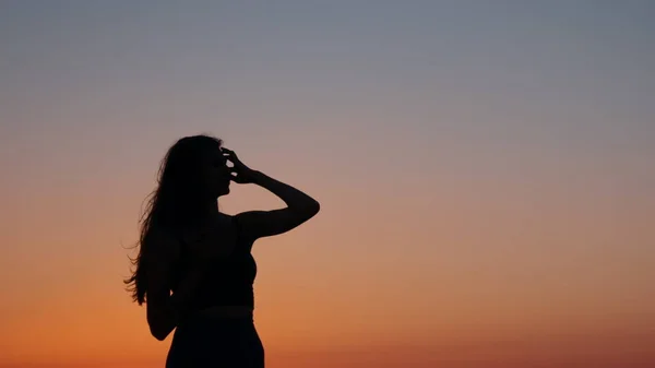 Silhouette einer Frau, die sich nach abendlichen Übungen am Strand ausruht — Stockfoto