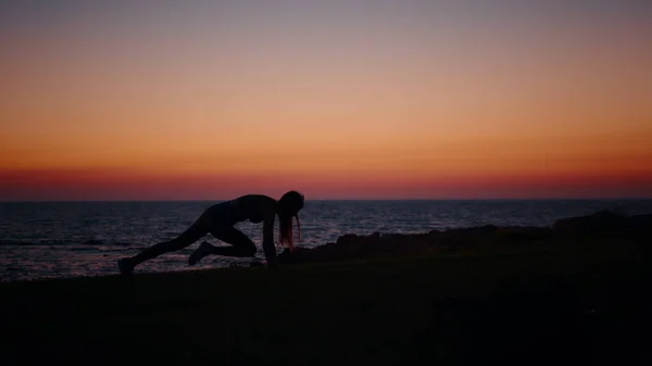 Donna in silhouette in piedi in posizione plancia vicino all'oceano — Foto Stock