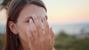 Kumsalda akşam antrenmanı sırasında dinlenen sportif bir kadın. Kumsalda aktif idmandan sonra kameraya gülümseyen beyaz kadın portresi. Akşam vakti, açık hava antrenmanı.