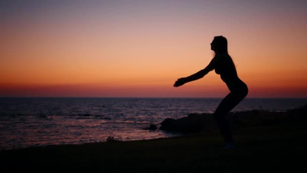 Fitness-Frau in Silhouette macht Kniebeugen-Übungen am Strand — Stockvideo