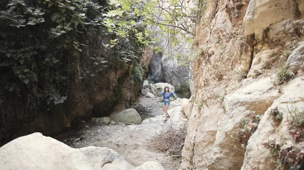 Woman in summer outfit walking along canyon of rocks