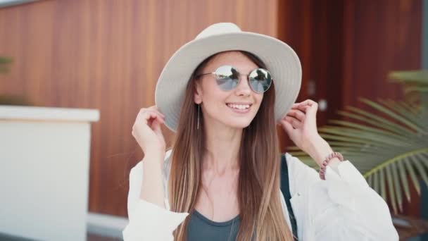 Adorabile donna in occhiali da sole e cappello in posa sulla strada della città — Video Stock