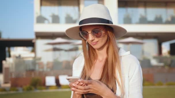 Bella donna in cappello e occhiali da sole utilizzando mobili all'aperto — Video Stock