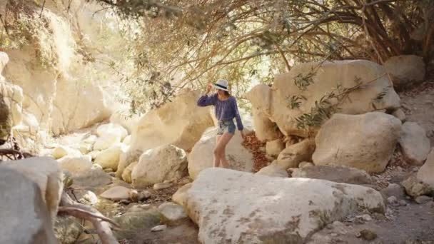 Γοητευτική γυναίκα με καλοκαιρινά ρούχα περπατώντας ανάμεσα σε ψηλά βράχια — Αρχείο Βίντεο