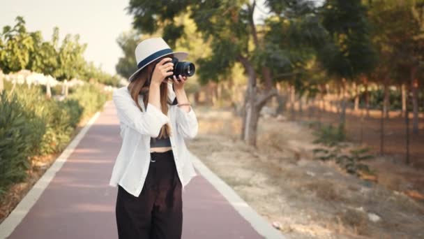 Mujer usando cámara digital para tomar fotos mientras camina — Vídeo de stock