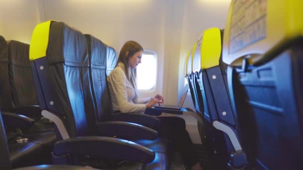 Πλευρική άποψη της γυναίκας που χρησιμοποιεί φορητό υπολογιστή για την εργασία στο εσωτερικό του αεροπλάνου — Αρχείο Βίντεο