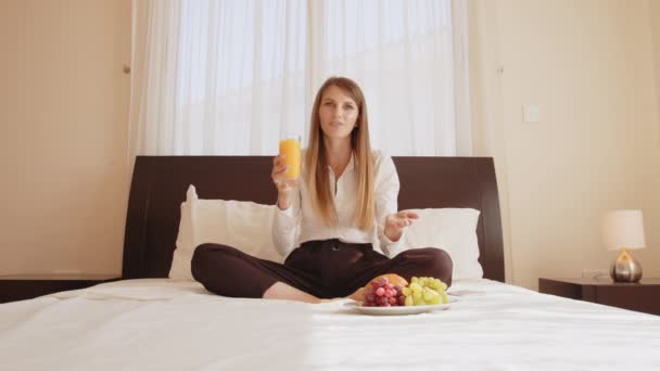 Nő beszél a kamera, miközben ül az ágyban gyümölcsökkel — Stock videók