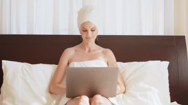 Kobieta pracuje na łóżku z laptopem, kończy pracę i zamyka laptopa. Kobieta leżąca w łóżku i surfująca po Internecie. Wolny strzelec pracujący w domu lub w hotelu. Praca zdalna z biura. — Wideo stockowe