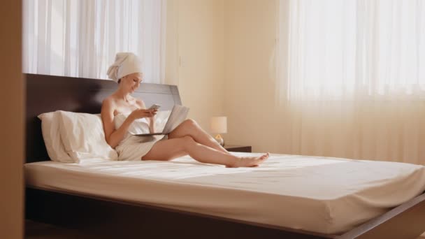 Otel odasında cep telefonu ve dizüstü bilgisayar kullanan bir kadın. — Stok video
