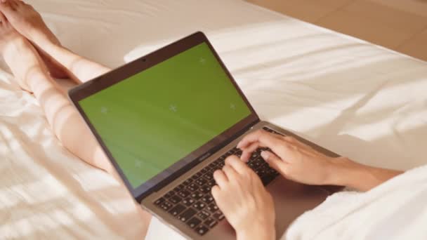 Kobieta leżąca na łóżku i pisząca na laptopie z zielonym ekranem — Wideo stockowe