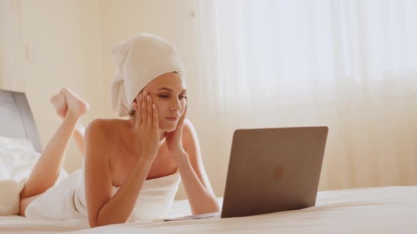 Frustrated woman lying on bed and looking on computer screen — Stock Video