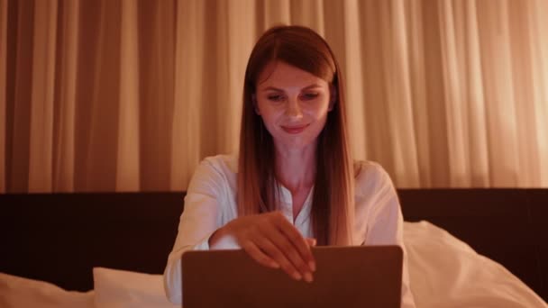 Mladá žena pomocí notebooku během večera na pokoji — Stock video