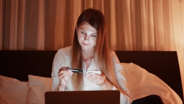 Kobieta korzystająca z telefonu komórkowego i karty kredytowej na wieczorne zakupy — Wideo stockowe