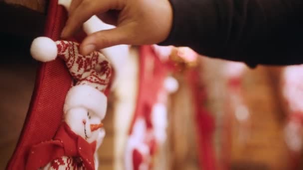 Ozdobná červená ponožka se sněhulákem visí nad krbem, ženské ruce opravují krásu. Nápad na vánoční ozdoby a šťastný konec roku. — Stock video