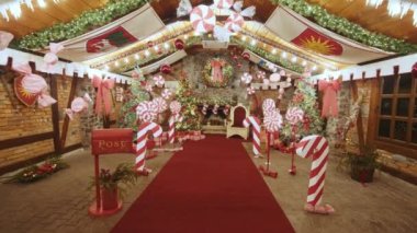 Lüks kırmızı Noel Baba tahtı. Etrafı hediye kutularıyla çevrili. Dekoratif posta kutusu Noel Baba atölyesi, paketlenmiş hediyeler Noel arifesinde kutular..