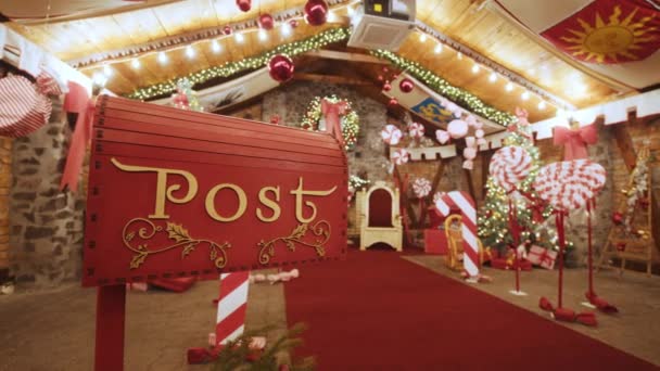 Closeup Rode brievenbus voor brieven aan Lapland aan de Kerstman. Kersttraditie. Decoratieve brievenbus Kerstman workshop, verpakt geschenken presenteert dozen op vakantie avond op kerst achtergrond. — Stockvideo