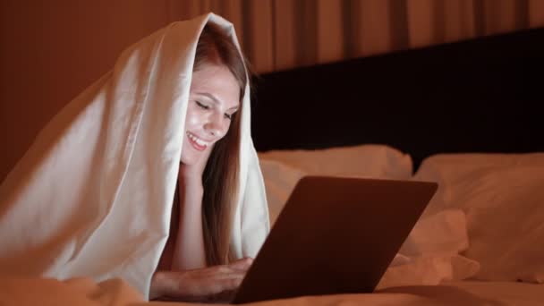 Frau liegt auf Bett und tippt nachts auf modernem Laptop — Stockvideo