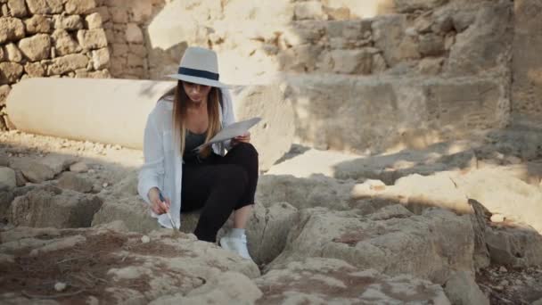Женщина чистит культурные артефакты щеткой на открытом воздухе — стоковое видео