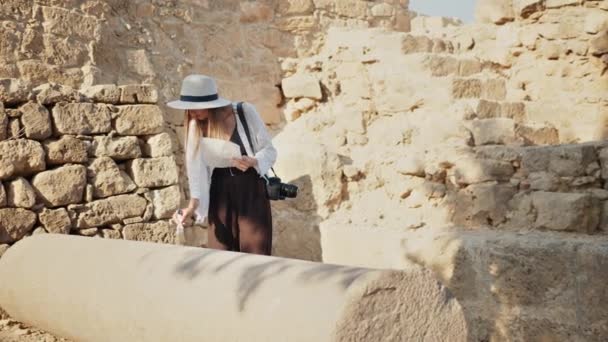 Археолог у капелюсі використовує пензлик для чищення стародавньої колони — стокове відео