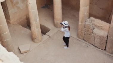 Kadın arkeolog antik binaların fotoğraflarını çekiyor.
