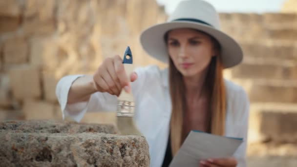 Жінка використовує пензлик під час археологічного копання — стокове відео