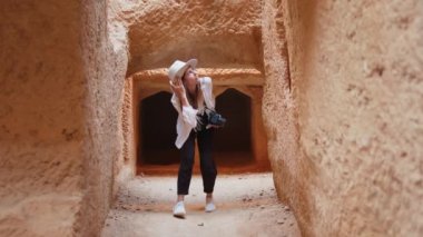 Antik tapınakta dijital kamerayla yürüyen kadın.