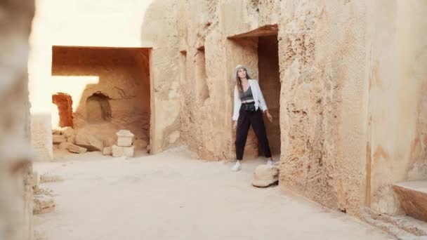 Arqueóloga mujer caminando entre edificio antiguo — Vídeos de Stock