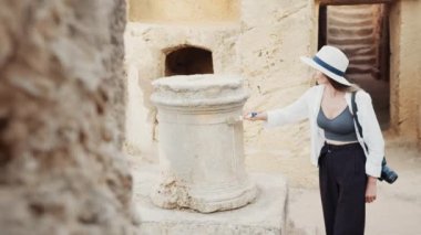 Eski tapınağın harabe sütunlarını fırçalayan kadın.