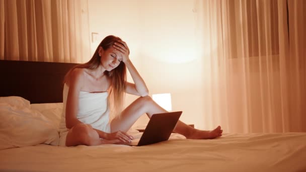 Moe vrouw met laptop op bed tijdens de avond tijd — Stockvideo