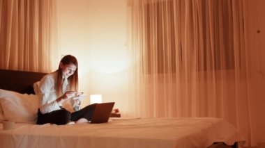 Yatakta uzanmış, kredi kartıyla alışveriş yapan güzel bir kadın. Yatağında dizüstü bilgisayarla oturan, online alışveriş yapan, kredi kartı kullanan bir kız. Öğrenci internet üzerinden alışveriş yapıyor