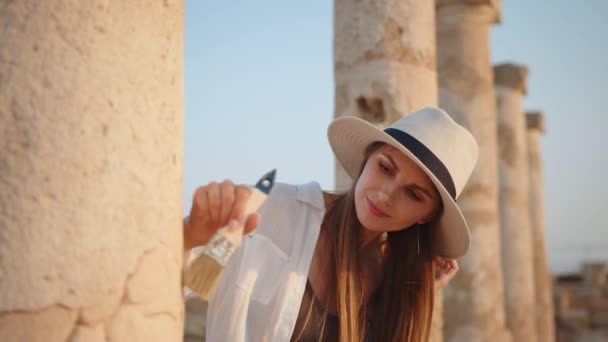 Retrato de la hermosa aventurera posando y mirando a la cámara. El gran arqueólogo con estilo que está parado con la civilización antigua, fósil permanece sitio arqueológico, ciudad olvidada en fondo — Vídeo de stock