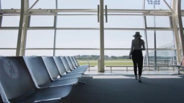 Havalimanı lobisinde yürürken gülümseyen güzel bir melez iş kadını başarılı bir şirket kariyerinin tadını çıkaran bağımsız bir kadın yönetici gibi görünüyor. Havaalanındaki kadın bir bilet almış.