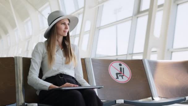 공항이나 기차역, 여성은 안전 한 거리를 유지하고 공항 터미널에서 노트북으로 일한다. 승객들은 치열 한 감염을 예방 한다. 프리랜서는 작업을 하고 대기실에서 비행을 기다린다. — 비디오