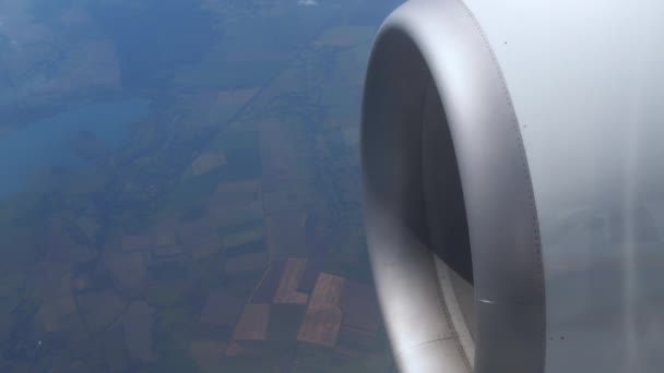 Η ιπτάμενη τουρμπίνα γυρίζει μια μηχανή. Σύννεφα αιωρούνται στον ουρανό σε μεγάλο υψόμετρο. Πτήση πάνω από το έδαφος. Άποψη του στροβίλου του αεροσκάφους και του διαδρόμου. αεροπλάνο κατά την πτήση, θέα από το παράθυρο του αεροπλάνου — Αρχείο Βίντεο