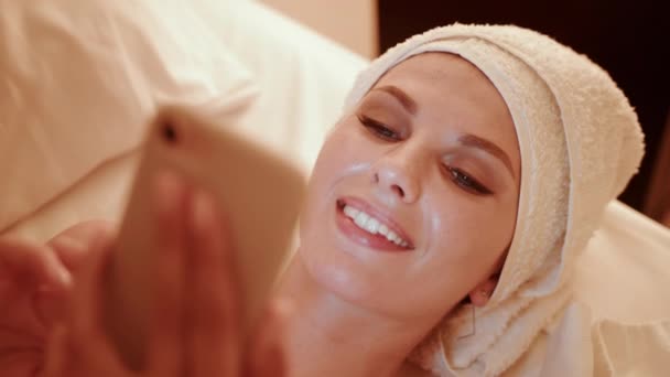 Mulher na cama à noite e usa um smartphone. Feminino usar telefone celular antes de dormir. As mulheres estão usando o telefone na cama, conceito de viciado em celular, luz azul prejudicial aos olhos. — Vídeo de Stock