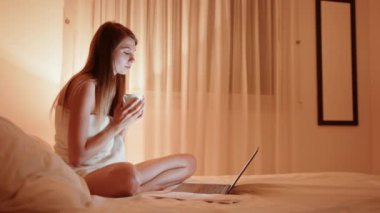 Gecenin bir yarısı genç bir kadın yatakta uzanıp kahve ya da çay içiyor ve telefondaki mesajlara bakıyor. Kadın, evinde elinde bir bardak sıcak içecekle akıllı telefonuna bakıyor..