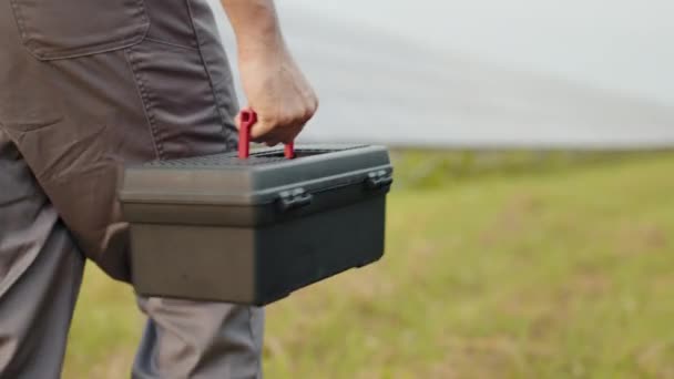 Close-up of a toolbox in the hand of a solar power engineer, the camera smoothly shows the face of a smiling engineer. The concept of repair and maintenance of solar panels. — Stock Video