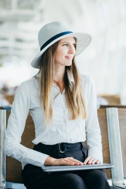 Güzel bir iş kadını havaalanındaki laptopta uçuş bilgilerini kontrol ediyor.